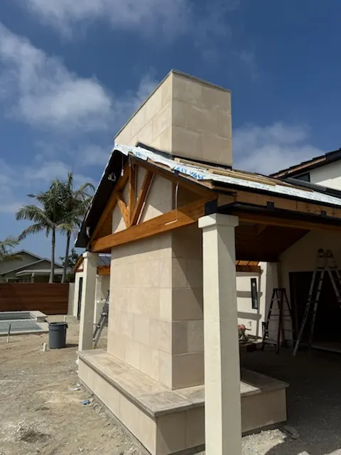 Stone veneer chimney and covered porch under construction on a two-story home