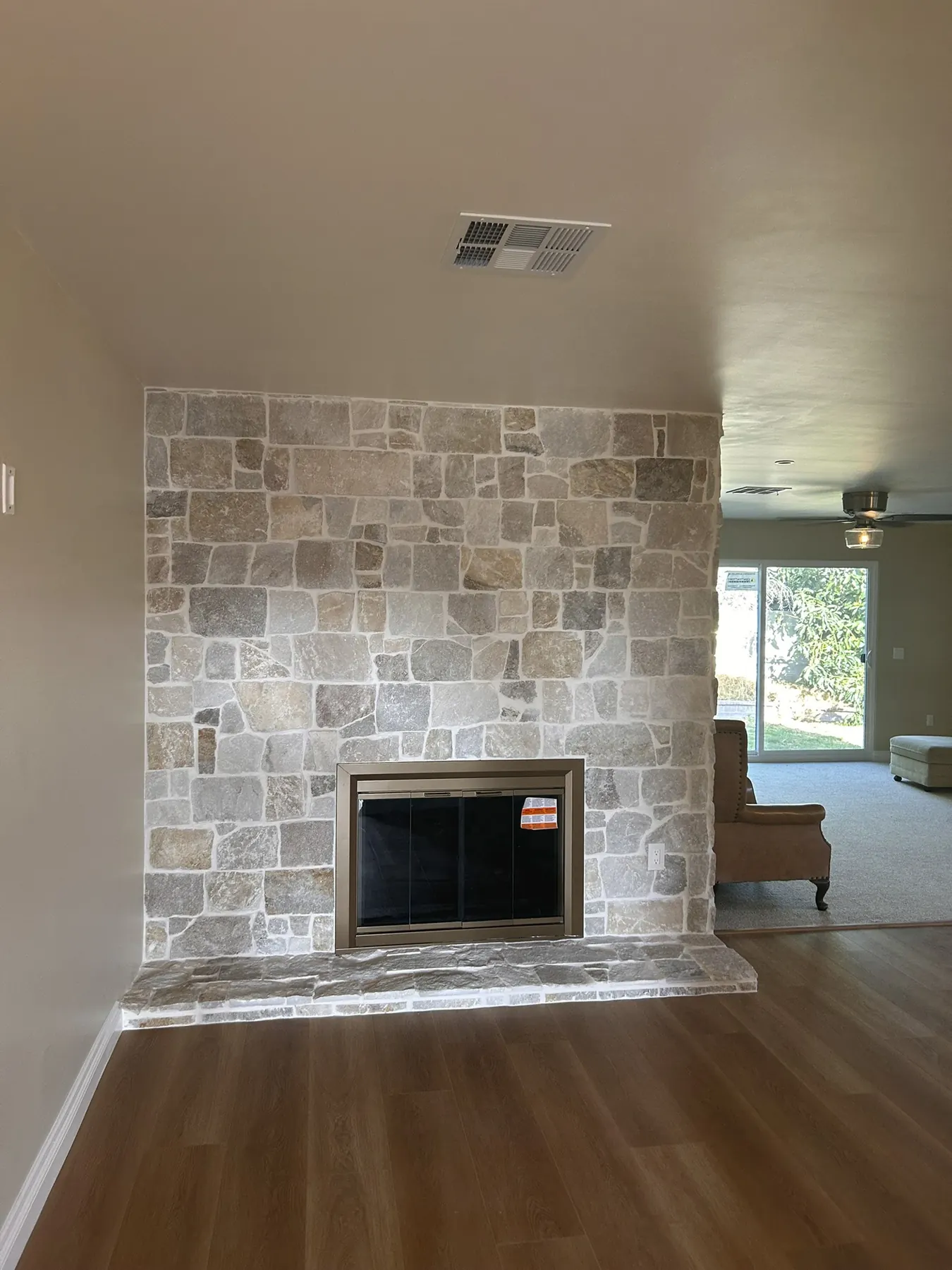 Finished stacked stone fireplace surround in a living room with wood flooring