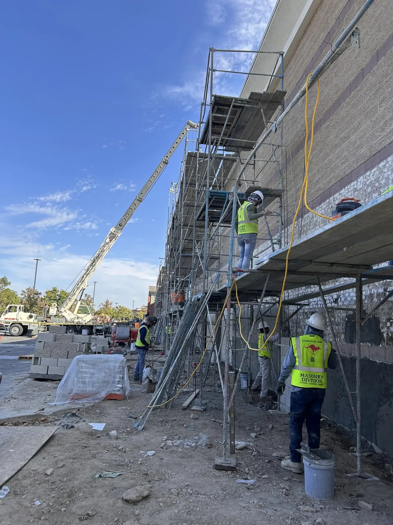 Masonry crew on scaffolding installing brick veneer on a commercial building