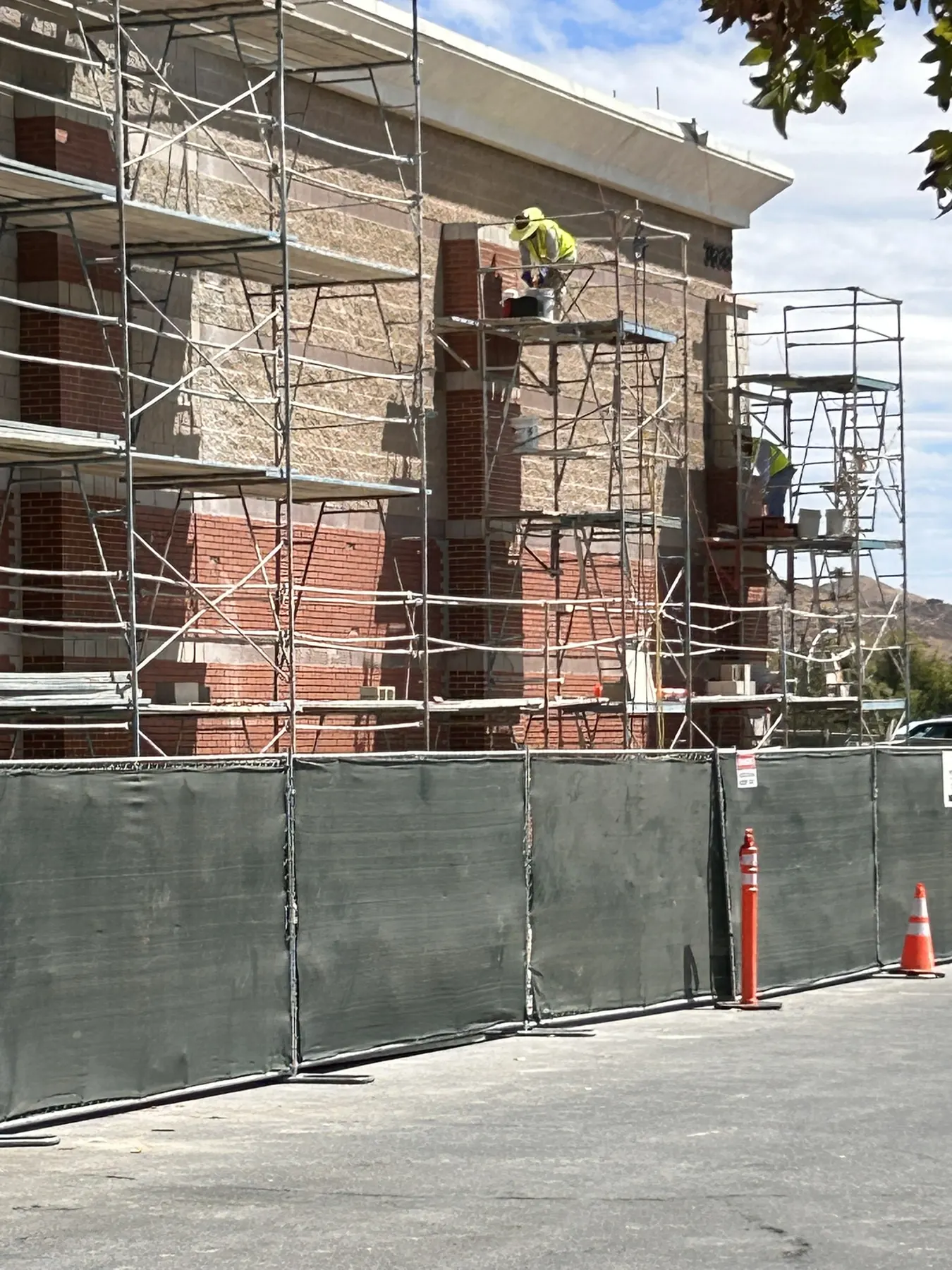 Brick and stone columns on a commercial building behind construction screening