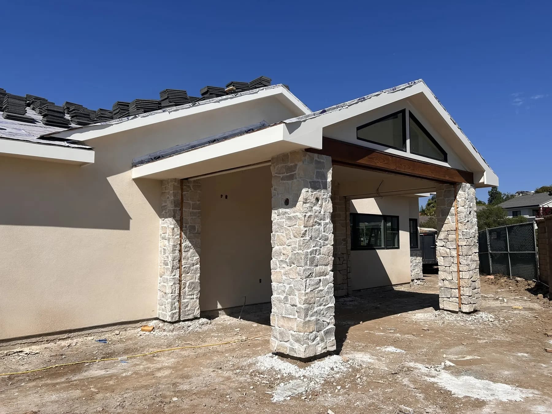 Stone veneer columns supporting a covered patio with a wood beam