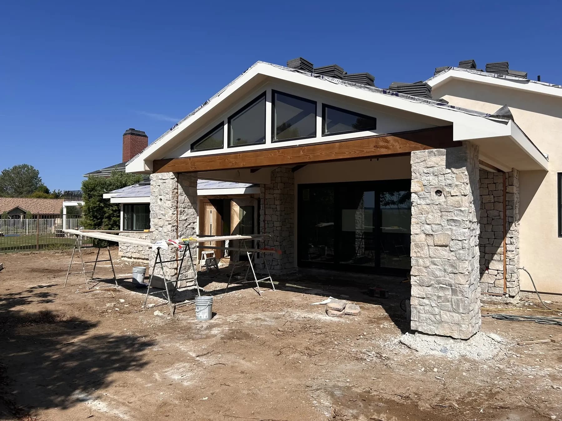 Stone veneer columns and a wood beam framing a home's covered entry